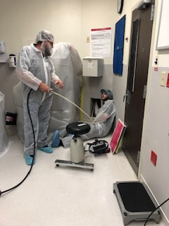 Two team members wearing protective gear with cleaning air ducts